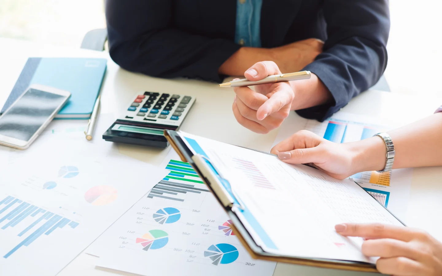 Project planning session with Atticus Consulting Hospitality Experts reviewing charts, procurement metrics, and construction documentation