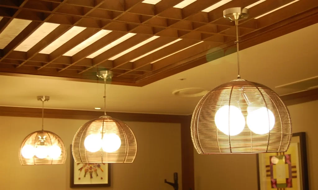 Three dome pendant lights with woven metal frames showcasing warm custom lighting in a hotel interior.